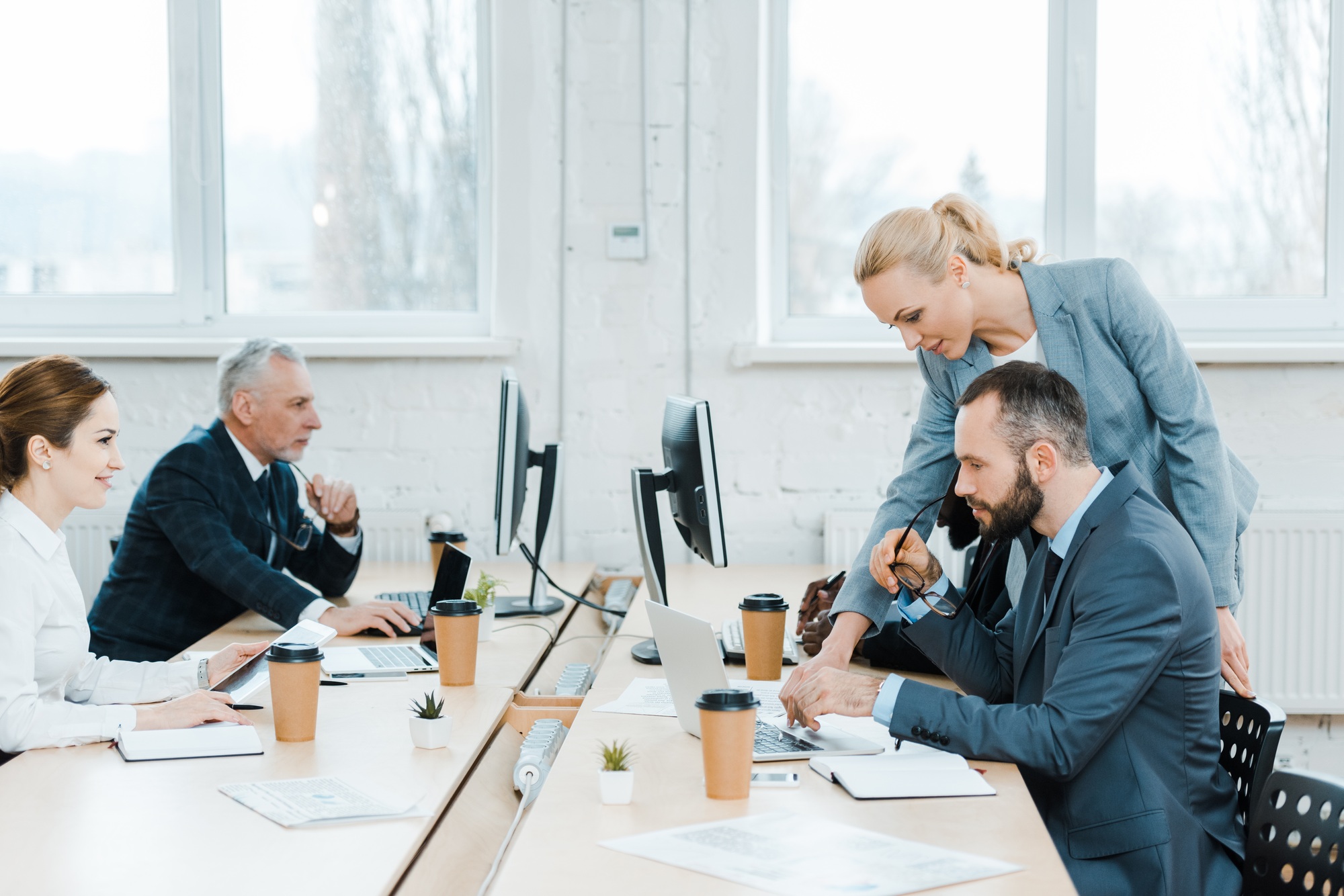attractive business coach near multicultural colleagues in office