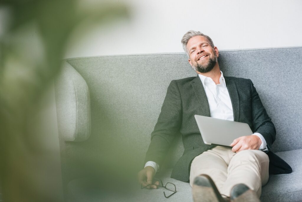 Businessman with laptop, relaxing on coach